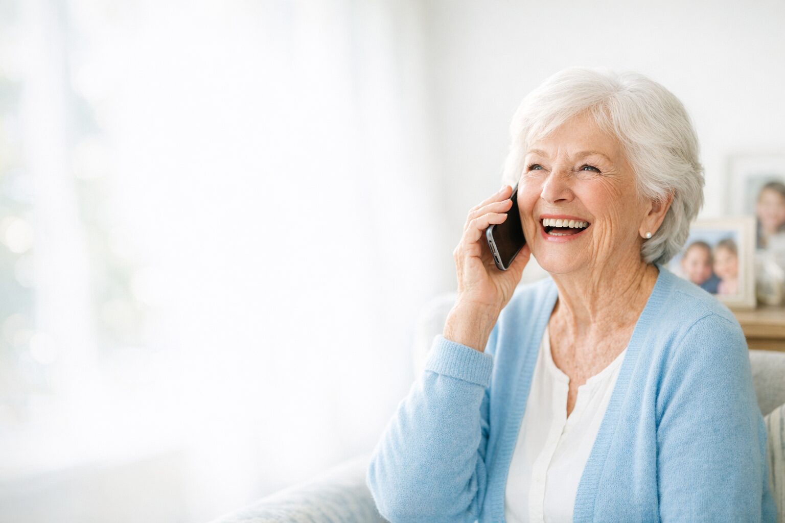 A radiant grandmother on the phone, photos of her grandchildren beside her
